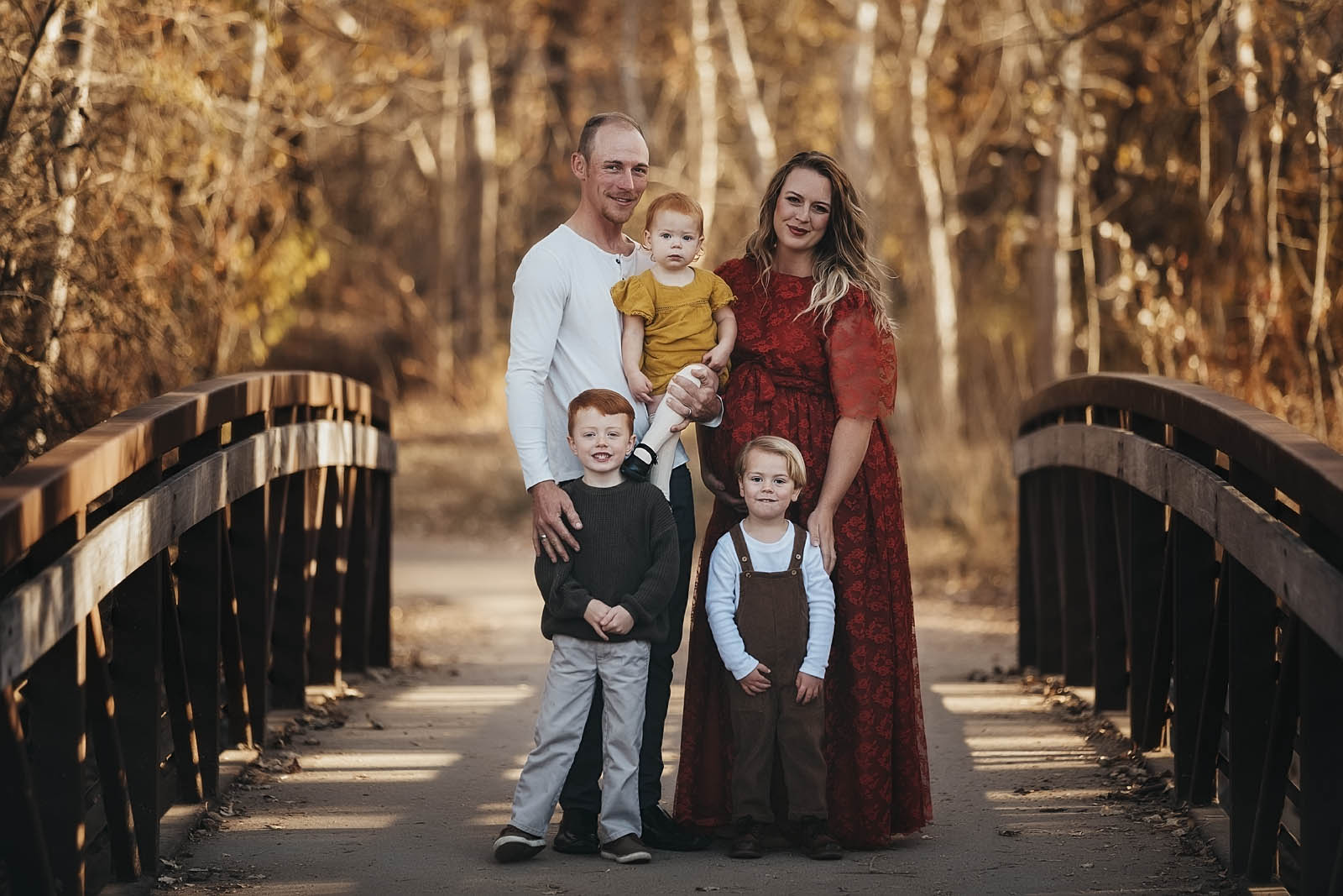 Family Photographer: Beautiful family of five standing on a bridge with mom and dad holding baby and all smiling