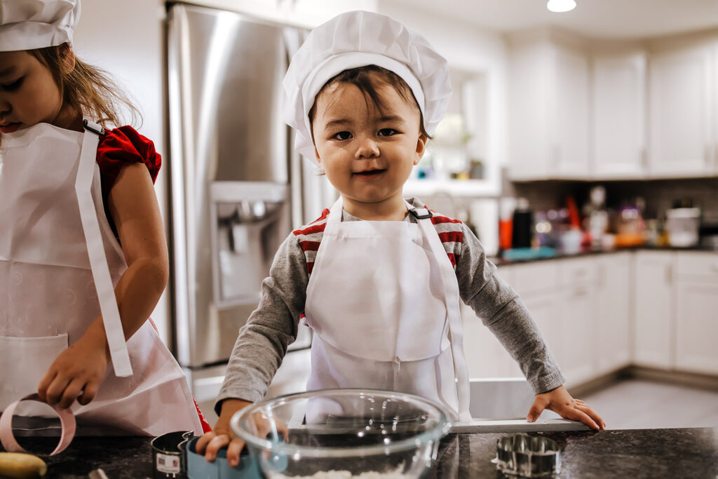 cute little boy in chef hat baking in a kitchen