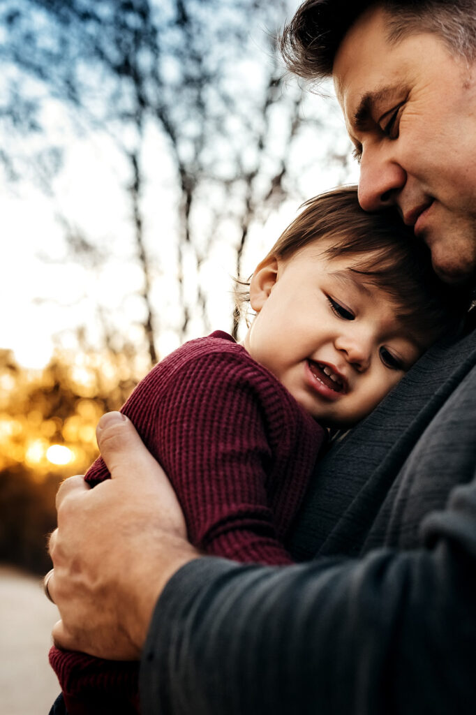 dad holding baby boy who is leaning against his chest and both are smiling