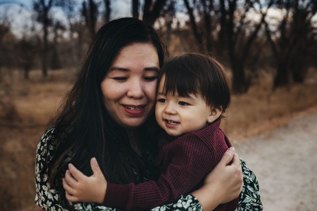 mom with dark hair holding boy toddler hugging each other and smiling