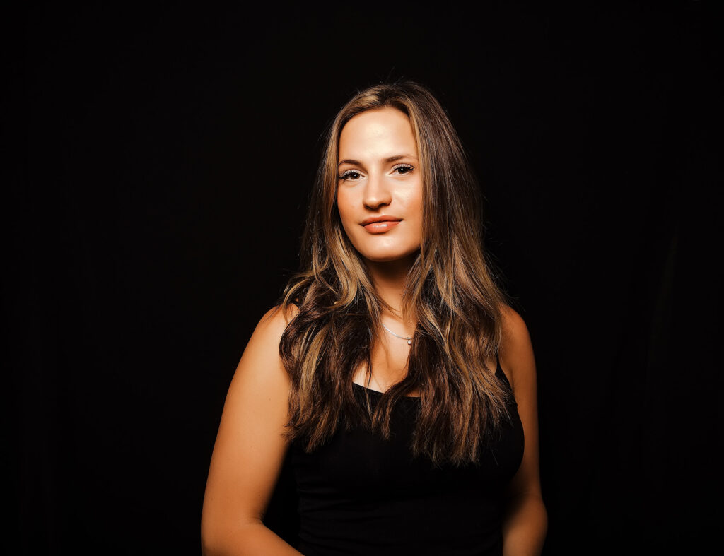 young blond woman wearing black tank top on black backdrop